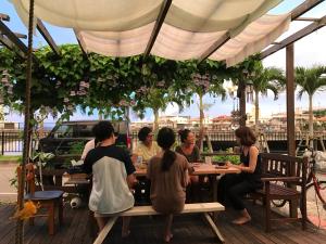 un grupo de personas sentadas en una mesa bajo un dosel en Minshuku Agaihama, en Yonabaru