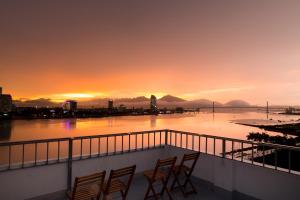 a group of chairs on a balcony with a sunset at Vitalis Riverside Hotel in Danang