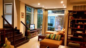 ein Wohnzimmer mit einem Sofa, einem TV und einem Fenster in der Unterkunft Teddy Bear Villa Hua Hin in Cha-am