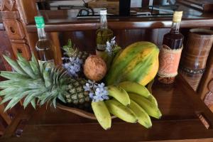 a pineapple and bananas on a table with wine bottles at Le Zahir Lodge in Ambatoloaka