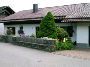 a house with a tree and flowers in front of it at Ferienwohnung Stilla Traurig in Arrach