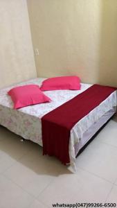 a bedroom with two beds with red pillows at Hostel Fariafaz in Gaspar
