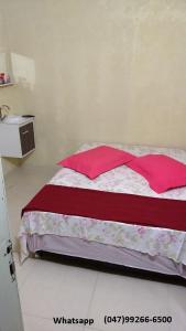 a bedroom with a bed with red pillows on it at Hostel Fariafaz in Gaspar +8 photos