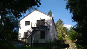 a white house with a balcony and trees at La cave au chat'pitre 'Le Fenil' in Villers-le-Bouillet