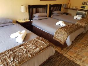 a hotel room with three beds with blankets at Kgosi Lodge in Kimberley