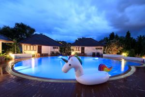 a pool with a unicorn float in front of a house at Baan Suan Nuanta in Samut Songkhram