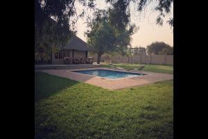 a swimming pool in a yard with a playground at Esmarline Lodge in Brits