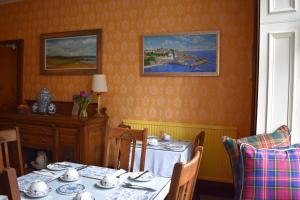 uma sala de jantar com uma mesa e cadeiras e um quadro em Montague Guest House em St. Andrews