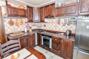 a kitchen with wooden cabinets and a stainless steel refrigerator at Vaizdas į marias in Nida
