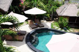 a swimming pool with umbrellas and chairs and a swimming pool at Gili Flush Harmony in Gili Trawangan