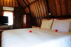 a bedroom with a white bed with red flowers on it at Gili Flush Harmony in Gili Trawangan