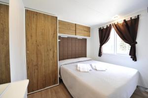 um quarto com uma cama branca e uma porta de madeira em Camping Bella Italia em Peschiera del Garda