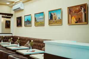 a row of tables in a restaurant with paintings on the wall at L'image Art Hotel in Yerevan