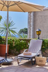 una silla y una sombrilla en el patio en Petit Hotel Ses Rotges - Only Adults, en Cala Ratjada