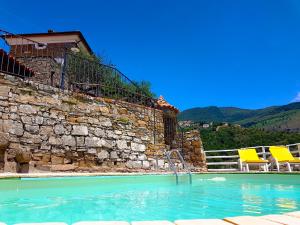 einen Pool mit zwei gelben Stühlen neben einer Steinmauer in der Unterkunft Il Canale 1861 in San Mauro Cilento