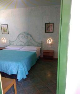 a bedroom with a bed and two lamps on the wall at La Casa Dei Delfini in Lampedusa