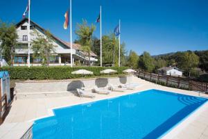 a swimming pool with chairs and umbrellas in front of a building at Hotel Pian del Sole in Sassello