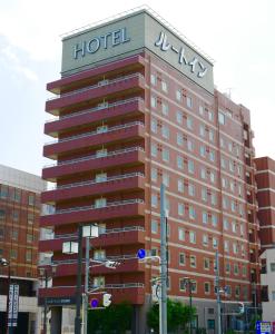 un bâtiment d'hôtel avec un panneau en haut dans l'établissement Hotel Route-Inn Fukaya Ekimae, à Fukaya