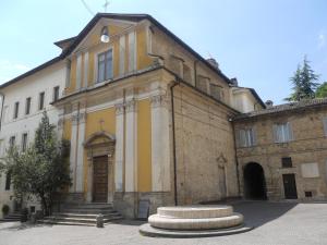 un edificio blanco y amarillo con una estatua delante de él en Nonna Bruna en Rieti