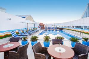 a hotel patio with tables and chairs and a swimming pool at Grand Excelsior Hotel - Bur Dubai in Dubai