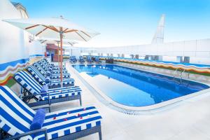 a large swimming pool with chairs and an umbrella at Grand Excelsior Hotel - Bur Dubai in Dubai