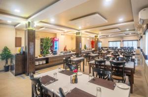 een restaurant met witte tafels en zwarte stoelen bij Viceroy Beach And Spa Resort in Mandarmoni