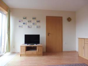 a living room with a television on a wooden cabinet at Ferienanlage direkt am Beetzsee in Radewege