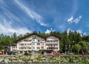 a large white building with trees in the background at Hotel Maria in Sils Maria