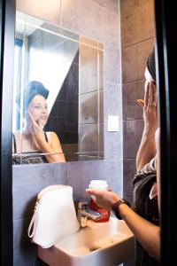 una mujer cepillándose los dientes delante de un espejo del baño en Amsterdam Hostel Orfeo, en Ámsterdam