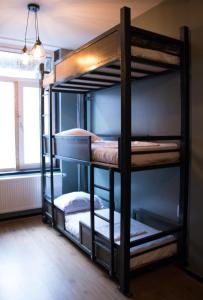a bunk bed with three bunk beds in a room at Amsterdam Hostel Orfeo in Amsterdam