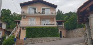 a yellow house with a balcony and a hedge at Apartman Ruza 1 in Poljane