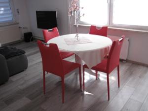 einen Esstisch mit roten Stühlen und einem weißen Tisch in der Unterkunft Spreewaldhaus Lübben in Lübben