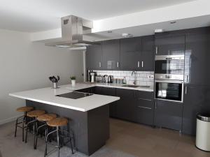a kitchen with black cabinets and a white island with stools at Stornoway Lido flats in Stornoway