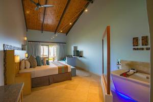 a hotel room with a large bed and a large window at Coco de Mer Hotel and Black Parrot Suites in Grand'Anse Praslin