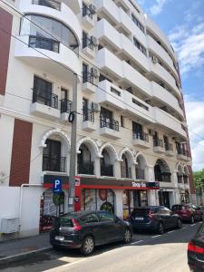 a large white building with cars parked in front of it at Studio Confort 4 in Bucharest