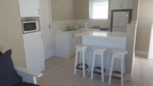 a kitchen with a white counter and stools in it at Island Nest in Knysna