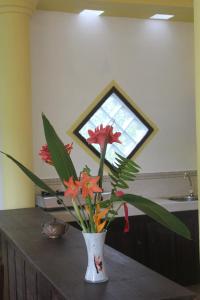 a vase with flowers on a table with a window at Dionis Villa in Unawatuna