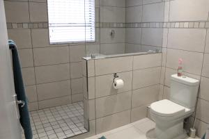 a bathroom with a toilet and a shower with a window at DCS Accommodation Cape Gate in Durbanville