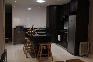 een keuken met apparatuur in zwart en wit en een aanrecht met krukken bij DCS Accommodation Cape Gate in Durbanville