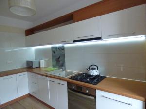 uma cozinha com armários brancos, um lavatório e um fogão em Apartament Blekit Nieba em Tykocin
