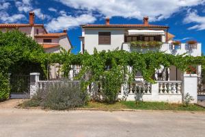 a white house with a fence and vines at Apartman D&D, Dvorine 63 in Banjole