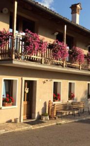 un edificio con un banco y flores en un balcón en Bed & Breakfast Col Mazzet en Belluno