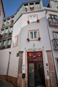 um edifício branco com flores nas janelas e uma porta em House Petit Lusa em Lisboa