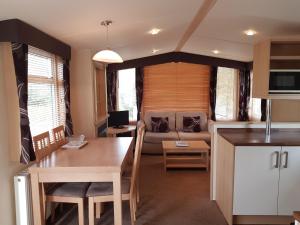 Una cocina y una sala de estar con una mesa y un sofá. en Sunnyglen Holiday Park, en Saundersfoot 33 fotos más