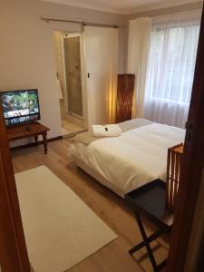 a bedroom with a bed and a flat screen tv at Protea Cottage in George