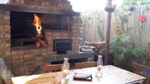 a wooden table in front of a brick fireplace at Protea Cottage in George