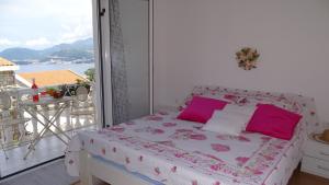 a bedroom with a bed with pink pillows and a balcony at Apartments - IRINA in Sveti Stefan