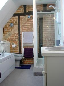 baño con lavabo, aseo y pared de ladrillo en The Old Stables B&B en Winslow