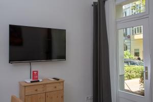 einen Flachbild-TV, der an einer Wand neben einem Fenster hängt in der Unterkunft Pandoras home in Berlin