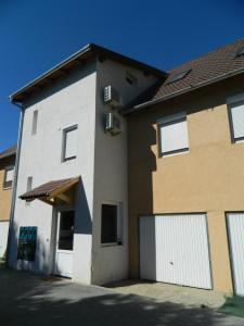 a house with white garage doors on the side of it at Greentó Apartman in Balatonföldvár